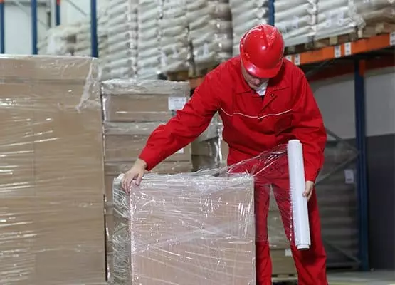 A man uses hand pallet wrap
